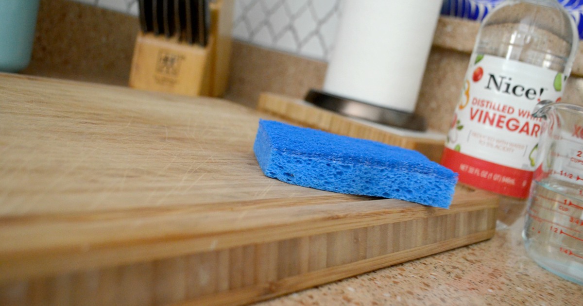 vinegar and a sponge on a wooden cutting board