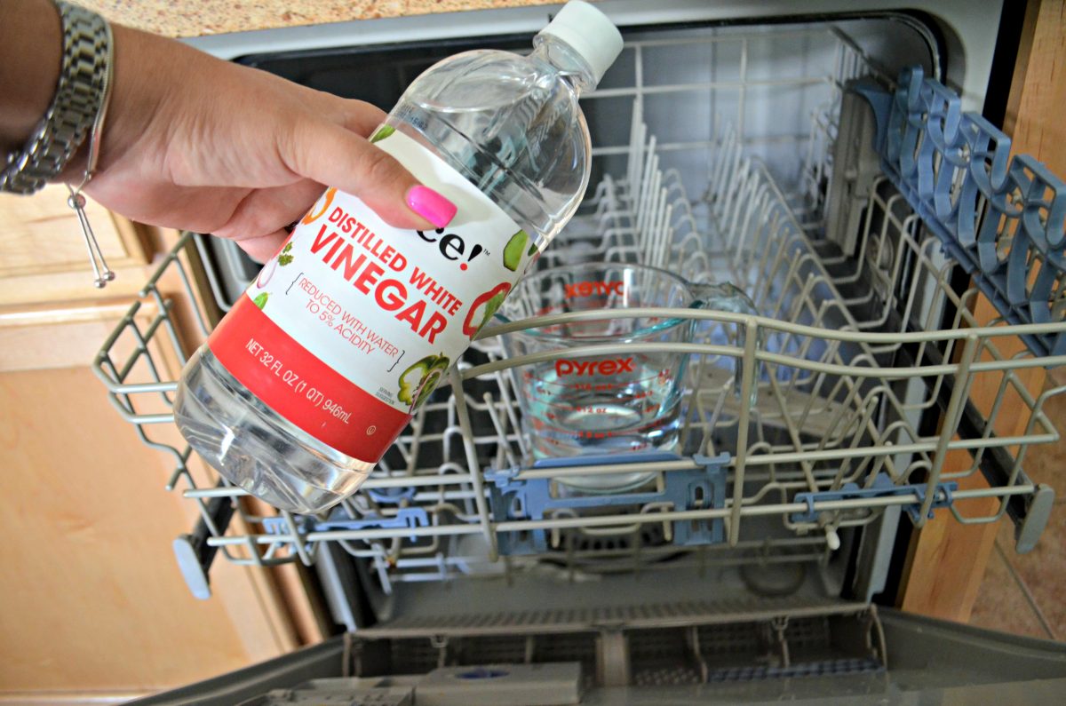 adding vinegar to a glass measuring cup in the dishwasher