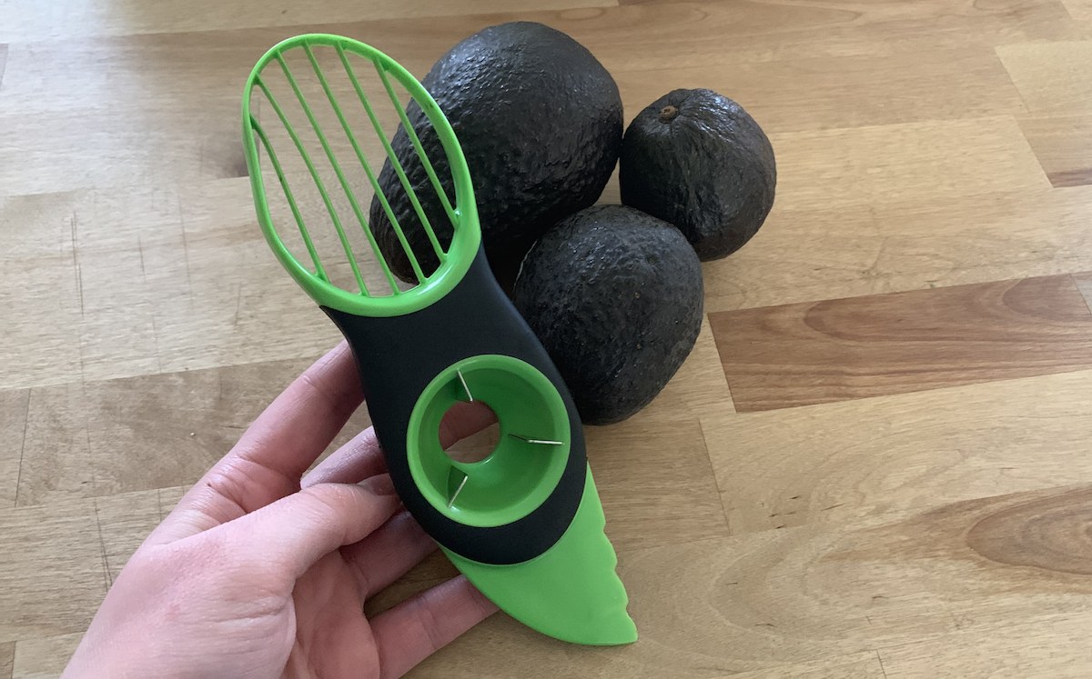 green avocado peeler knife with ripe avocados on the counter