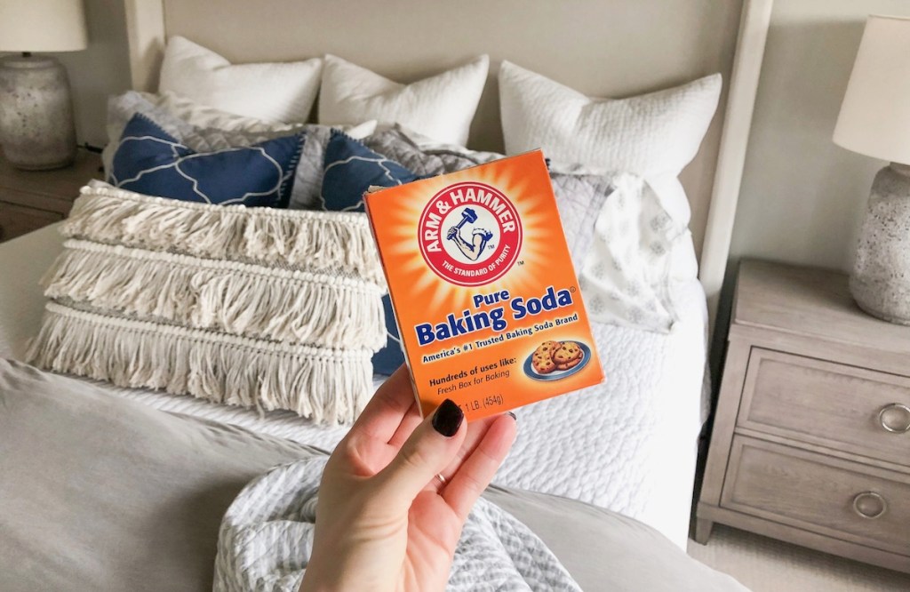 sara holding baking soda box with bed and pillows in the background
