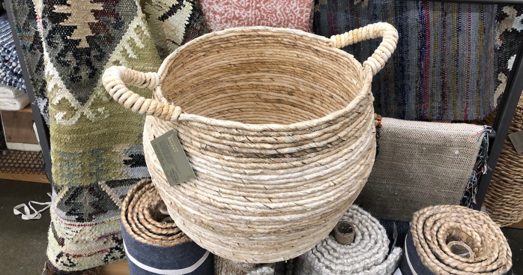 round woven basket with handles sitting on a pile of rugs