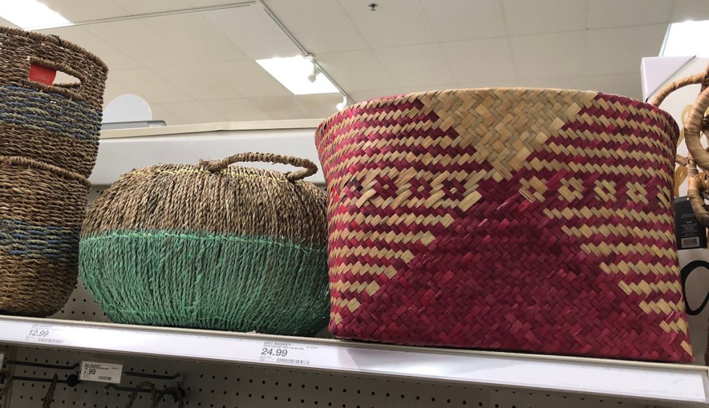 two seagrass woven baskets sitting on a shelf natural colored with blue green and burgundy 