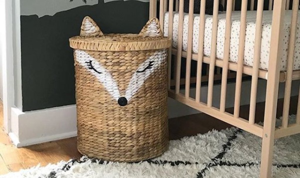 large fox shaped wicker basket sitting on rug next to crib