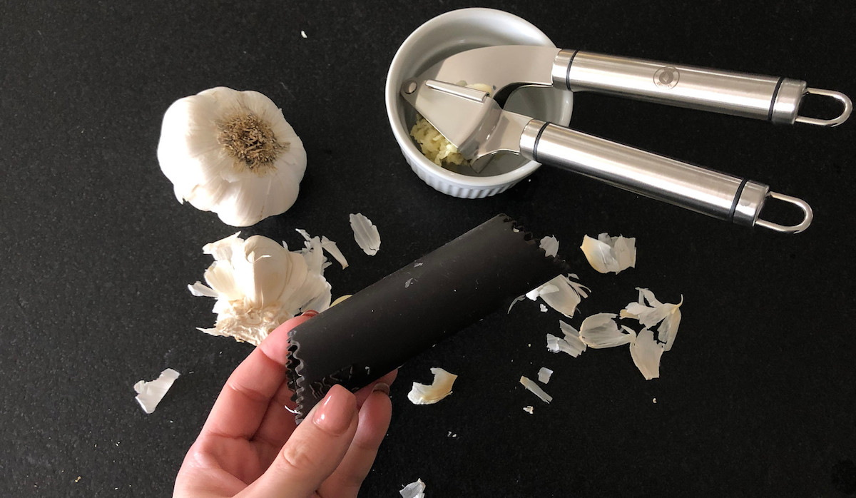 silicone roller with peeled garlic press and bowl in the background