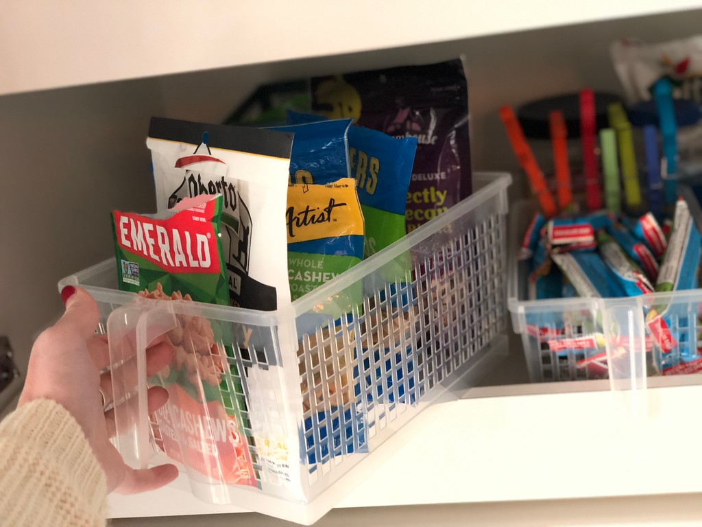 Pantry snacks stored in clear handled storage basket 