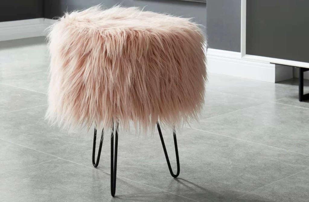 pink fur stool with black iron legs sitting on floor