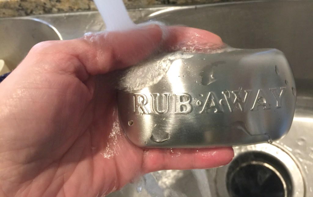 hand holding wet rub away stainless steel bar of soap 