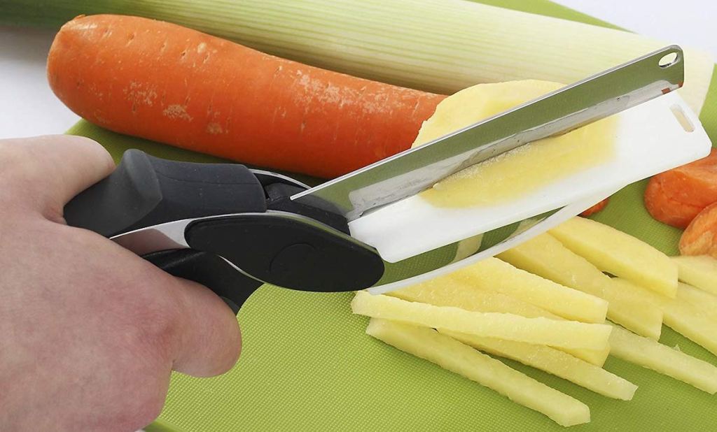 hand using scissors with cutting board to chop veggies