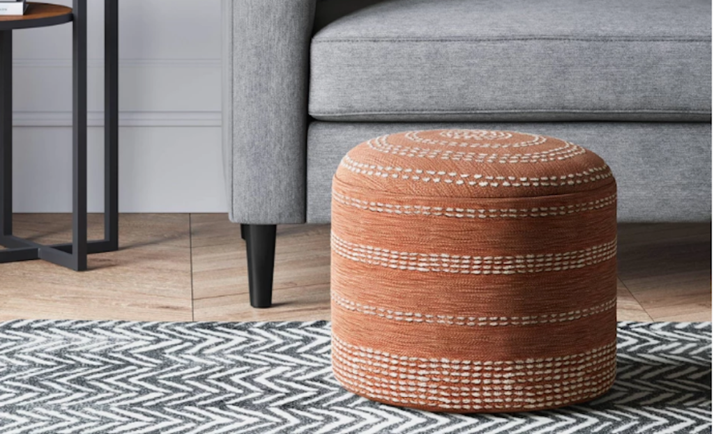 coral embroidered pouf sitting on the floor 