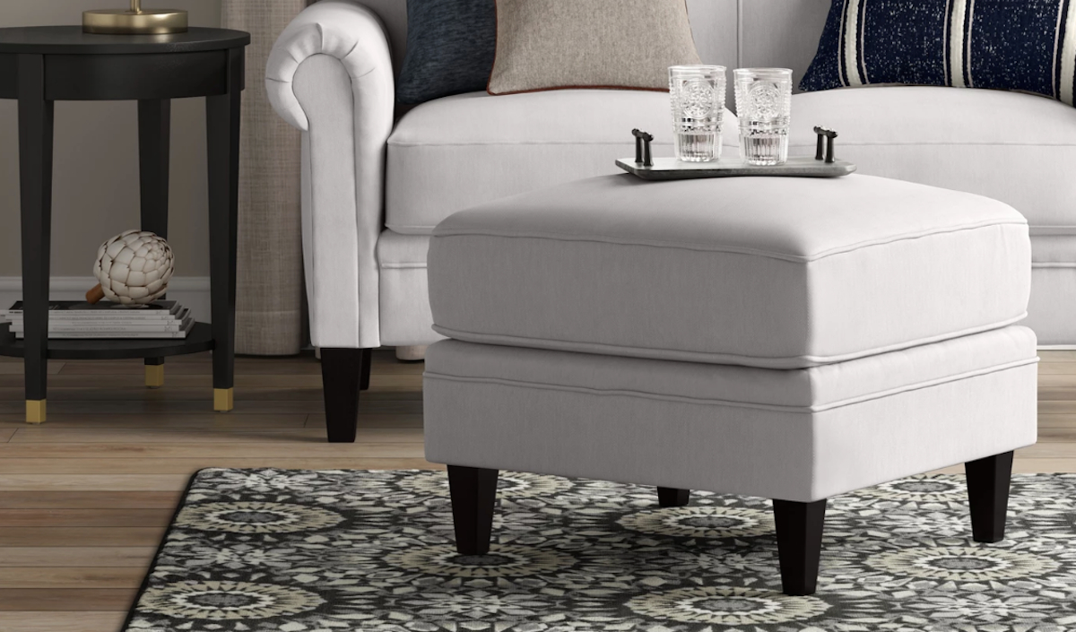 traditional style white ottoman sitting on the floor with two glasses and a tray on top
