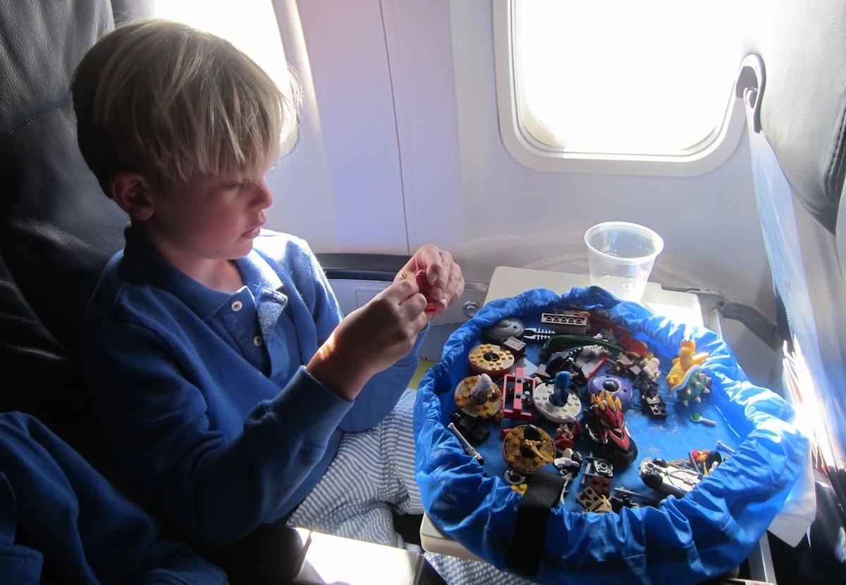 boy playing with toys on airplane with drawstring lay n go playmat 