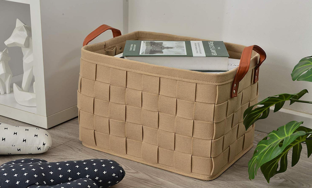 woven felt basket with leather handles sitting on floor with books