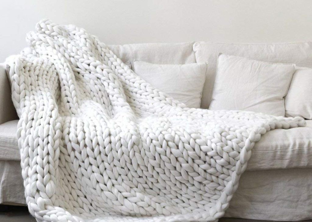 large white chunky knit blanket draped on an off white couch 