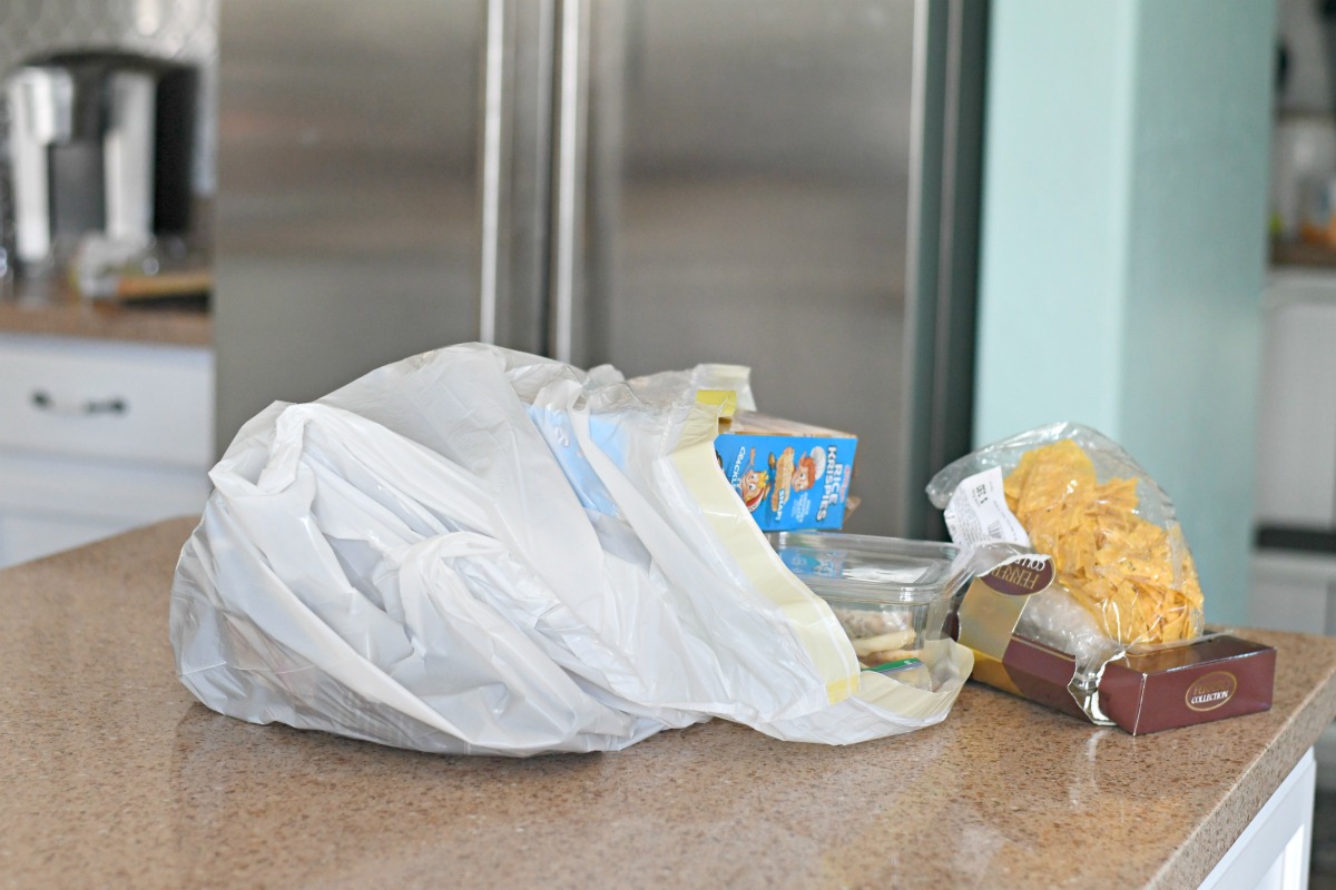 a plastic grocery sack with groceries on a counter