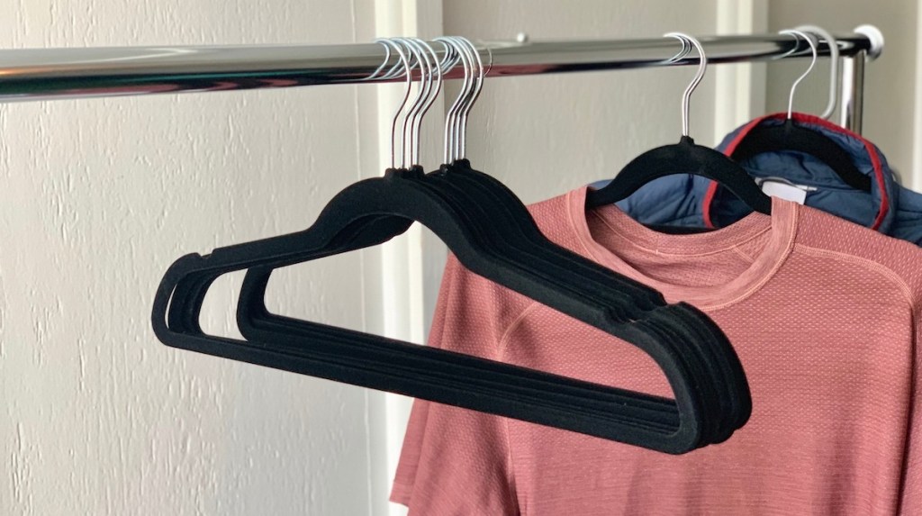 black velvet hangers hanging on a metal clothes rack with pink shirt
