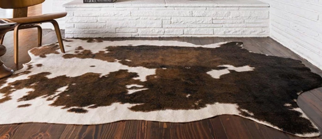 large cowhide rug laying on wood floor in front of white bricks