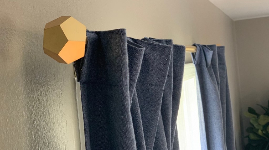 gold geometric curtain rods with blue chambray curtains hanging on gray wall
