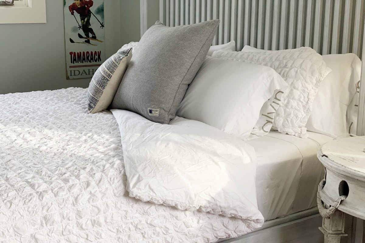 a bed made up with white sheets and a white duvet