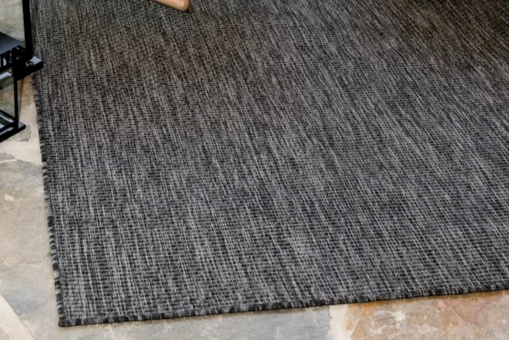 black charcoal colored rug on stone floor