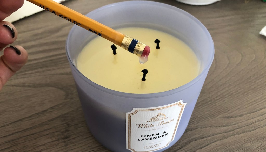 linen and lavender scented candle with melted wax and pencil dipped in wax