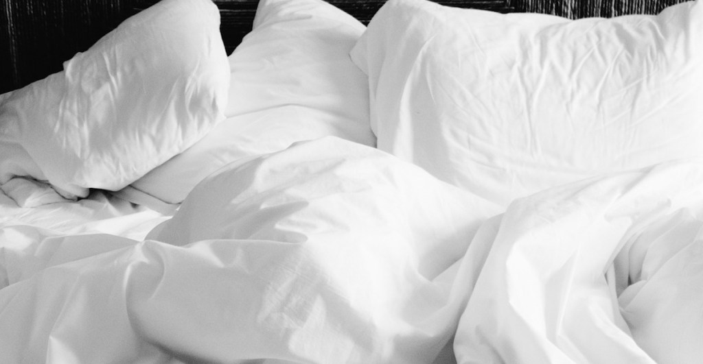 messy white bedding and pillows ruffled and disorganized on bed