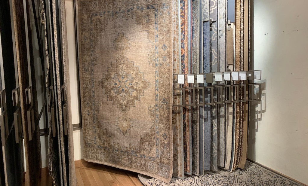 row of rectangular patterned rugs hanging on racks in a store