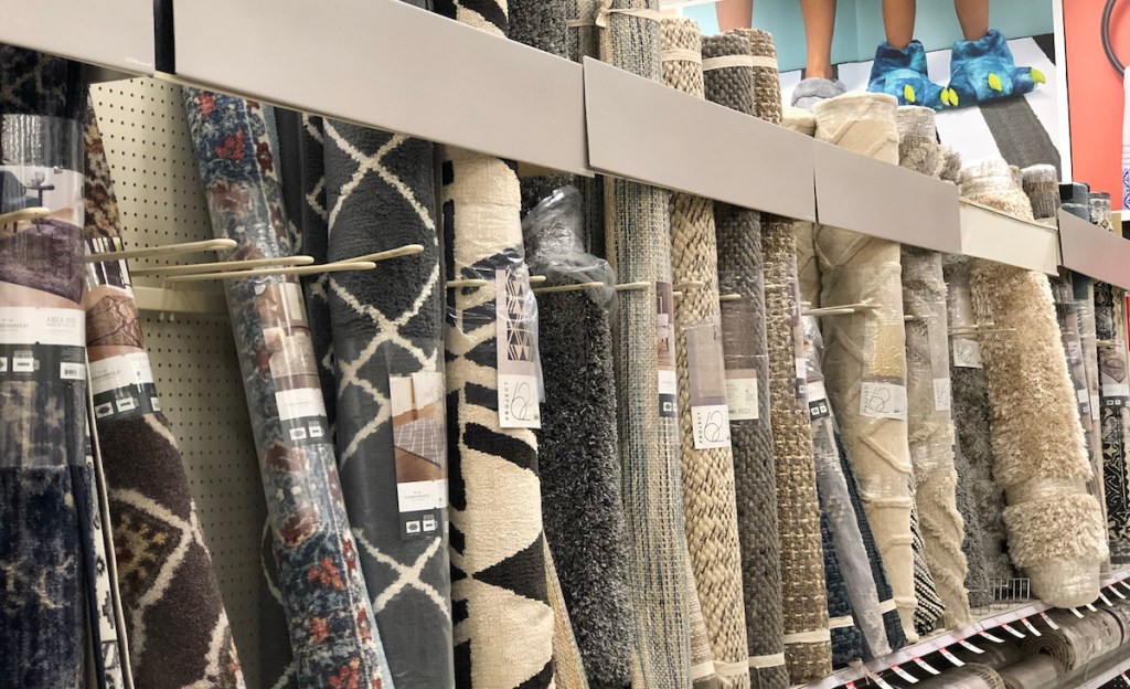 row of standing rolled up rugs on a store shelf