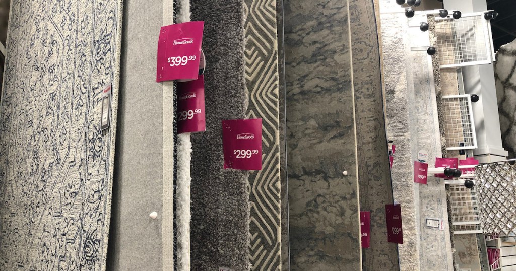 various colored rugs hanging up in store with pink price tags