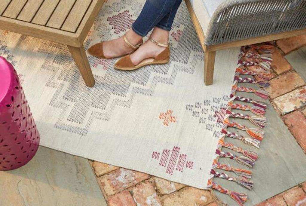 aztec print rug on concrete and brick with table and crossed feet