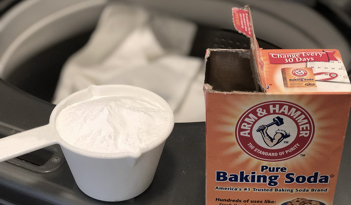 a measuring cup of baking soda next to a washing machine
