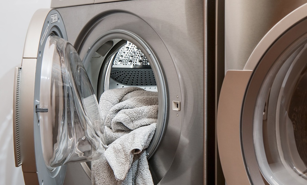 open front load washing machine with towel hanging out of door