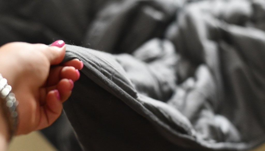 hand holding a dark gray weighted blanket