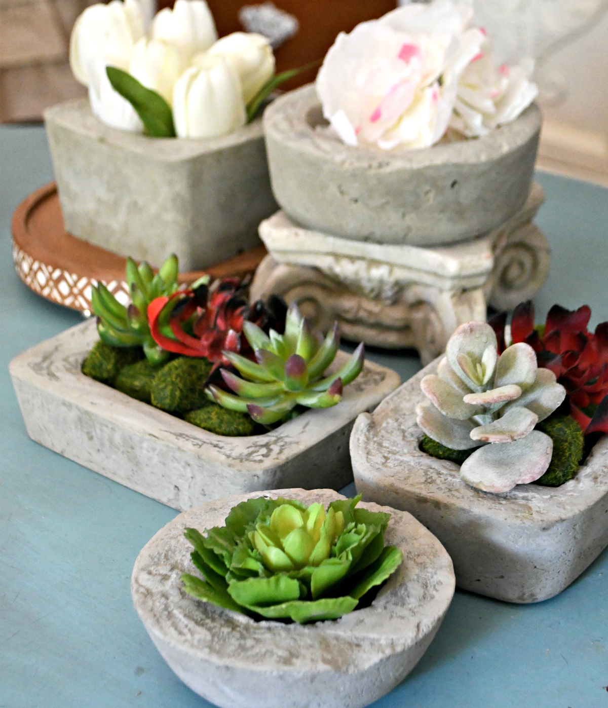 tabletop with a collection of concrete planters styled with flowers and succulents