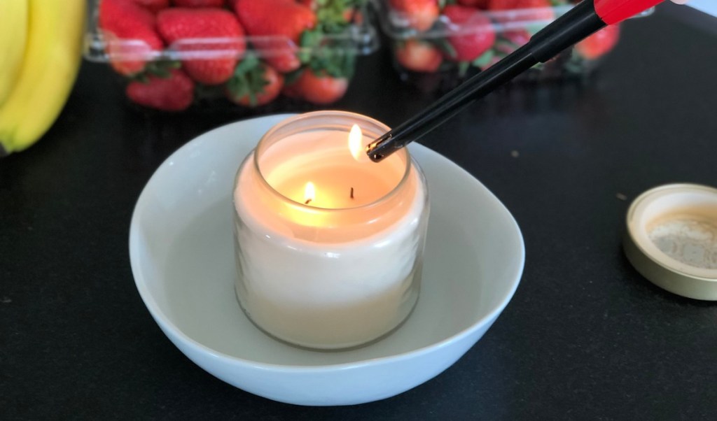 cream candle in white dish with water and fruit in the background
