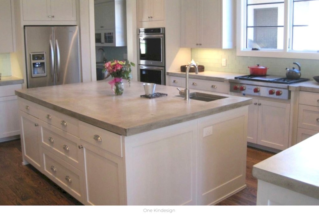 white kitchen cabinets with cement countertops with stainless steel appliances
