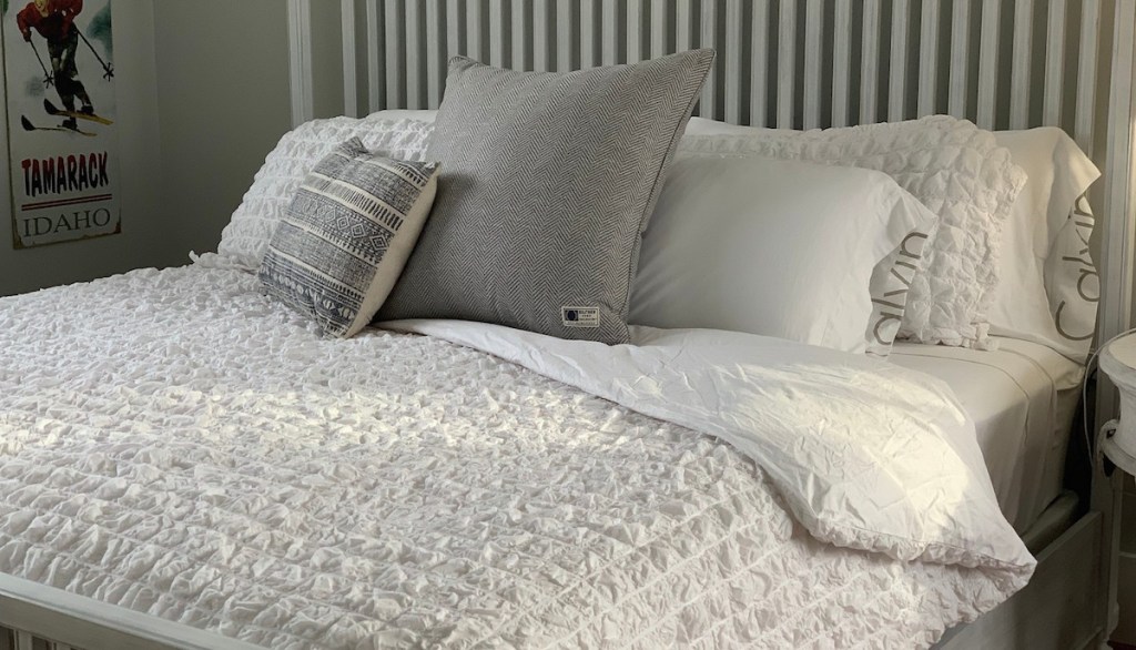 white and gray bedding on white framed bed in room with pillows