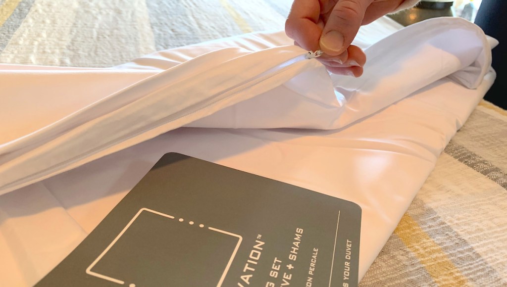 hand pulling on white zipper on blanket and gray paper with white writing
