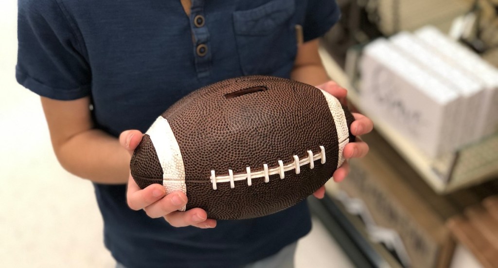 hands holding ceramic football bank 