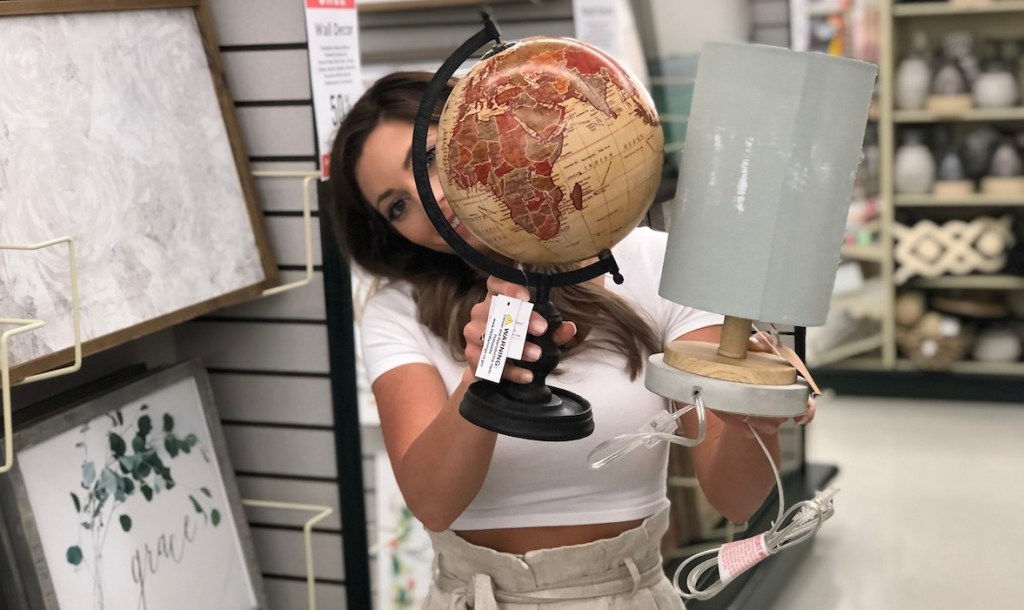 sara holding a vintage globe and gray tube light in store aisle
