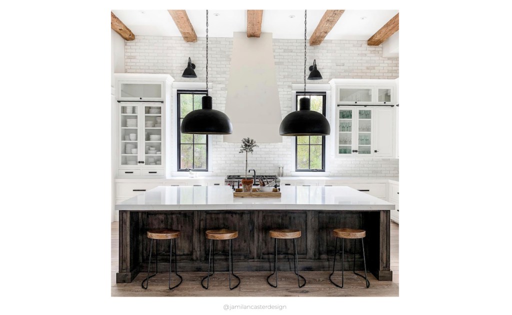 square photo of black and white kitchen with large pendants beams on ceiling and kitchen stools