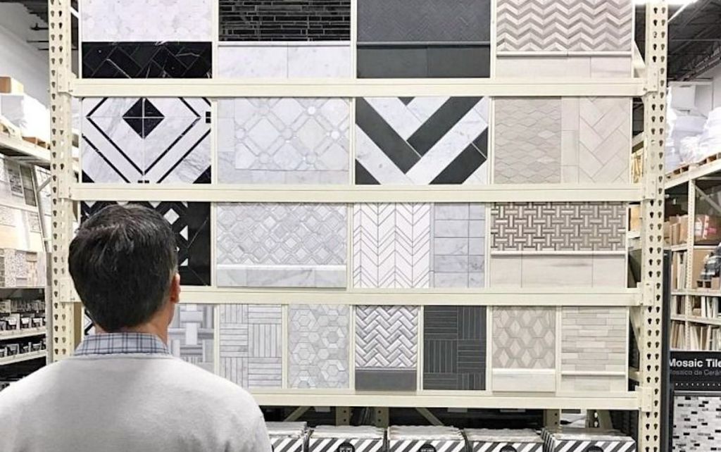 man standing in front of tile wall with different varieties of mosaic tile samples