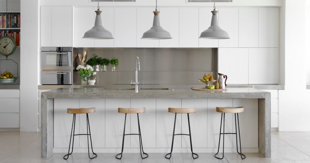 modern white and silver kitchen with four barstools and white pendant lights