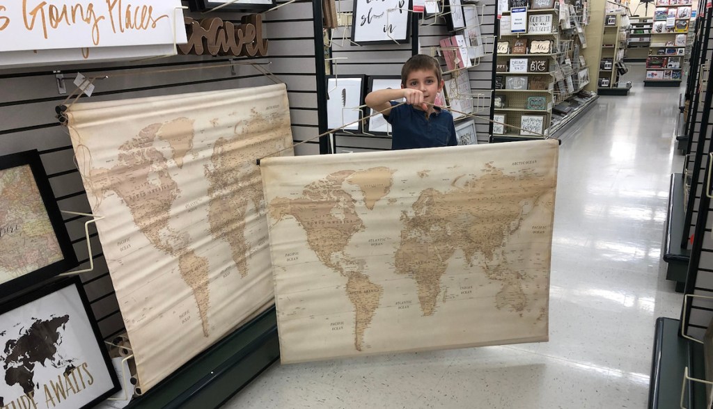 boys holding map tapestry in store aisle with maps hanging on shelf