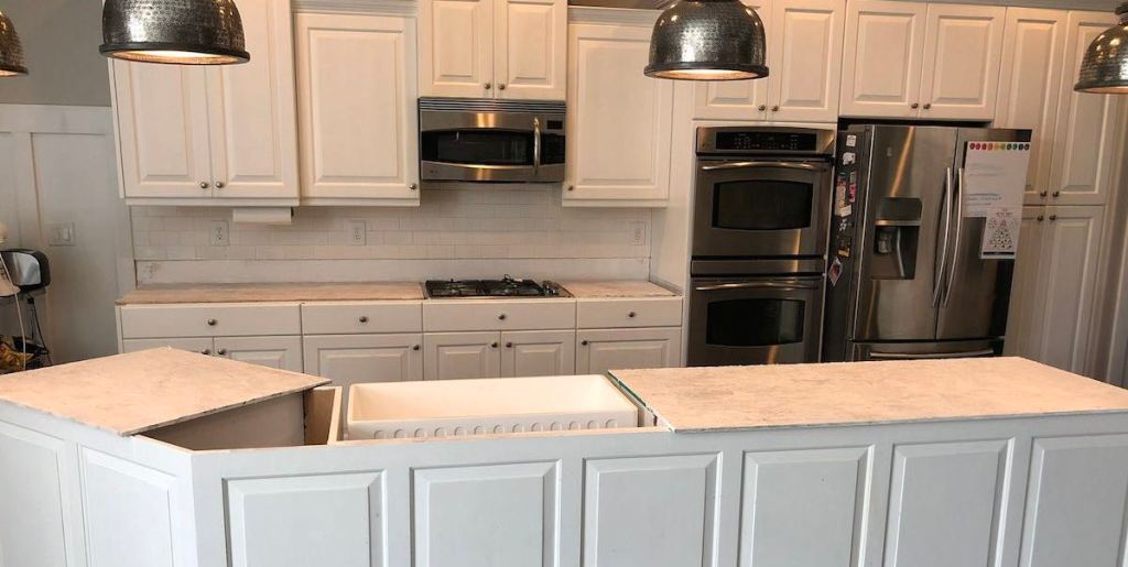 white kitchen cabinets with temporary plywood countertops and stainless steel appliances