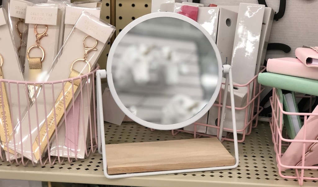 white round metal mirror on store shelf with pink decor