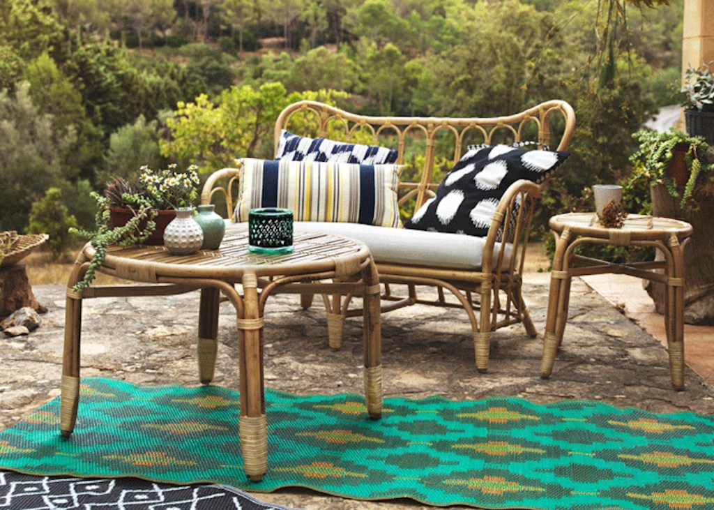 rattan loveseat with colorful pillows and matching coffee table with small accessories