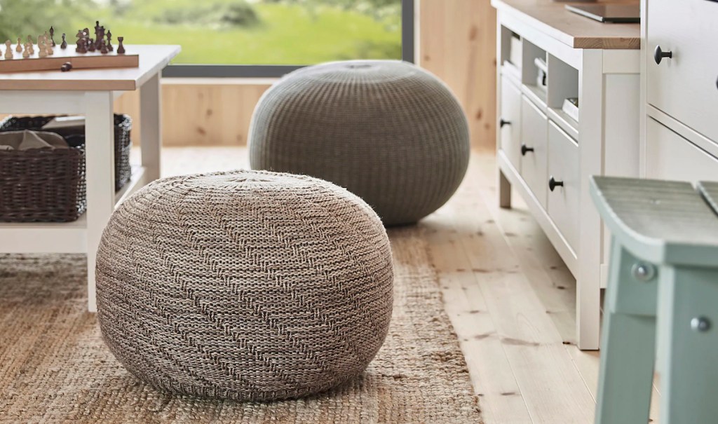 two round pouf ottomans sitting on jute rug with white cabinets to the right