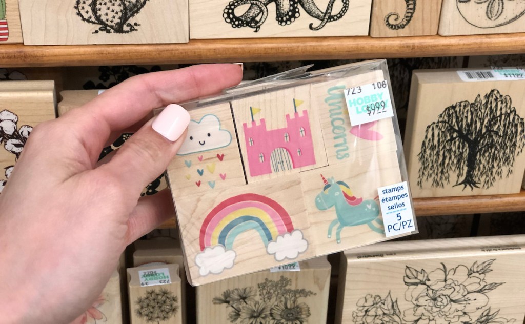 hand holding a pack of wooden stamps rainbow and unicorn theme