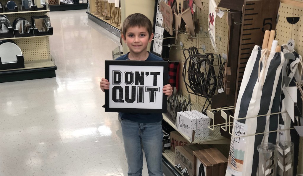 boy holding don't quit sign
