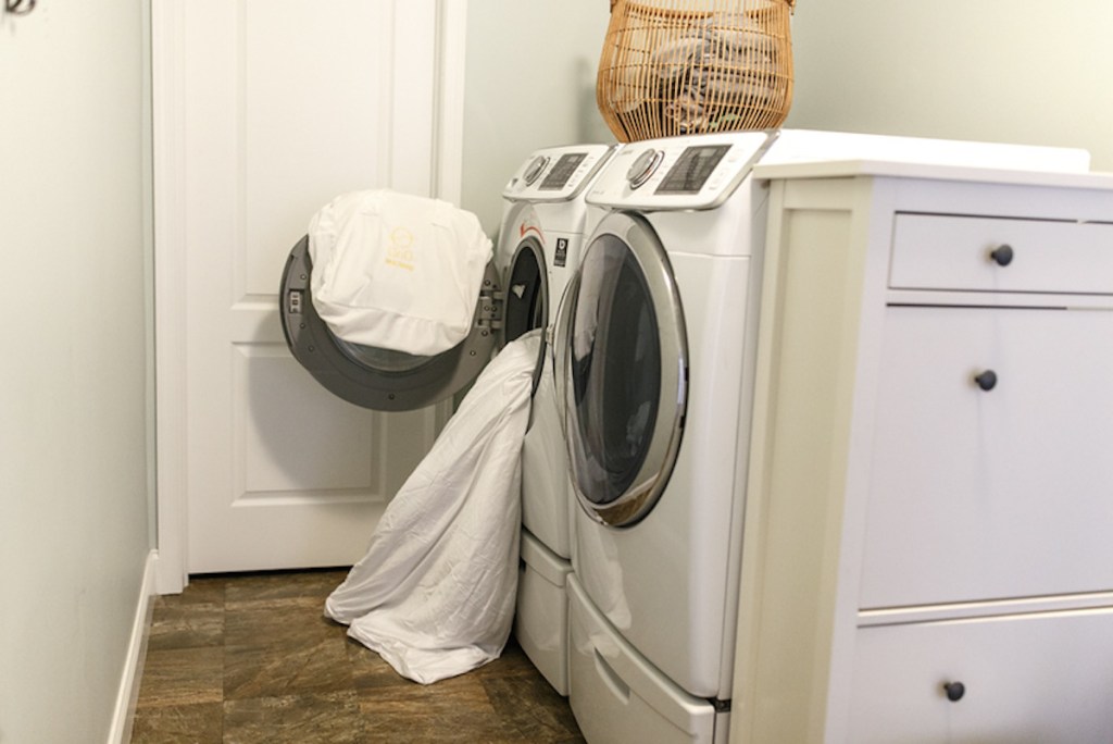 white front loading washing machine with white blanket cascading out 